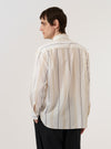 A model wears the Ecru/Navy/Sand Hendrix Stripe Square Pocket Shirt, shown from a rear three-quarter angle against a plain white background. The shirt features vertical stripes in ecru, navy, and sand, with a straight hem and short sleeves. The garment is constructed from a textured cotton fabric, and its relaxed fit and structured collar are prominent features.