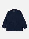 The Indigo Recycled Herringbone Kyoto Work Jacket is shown as a flat lay against a white background. The jacket features a collarless, wrap-style front with fabric ties, two large patch pockets at the waist, and one patch pocket on the left chest. The indigo-colored fabric has a visible herringbone weave texture.
