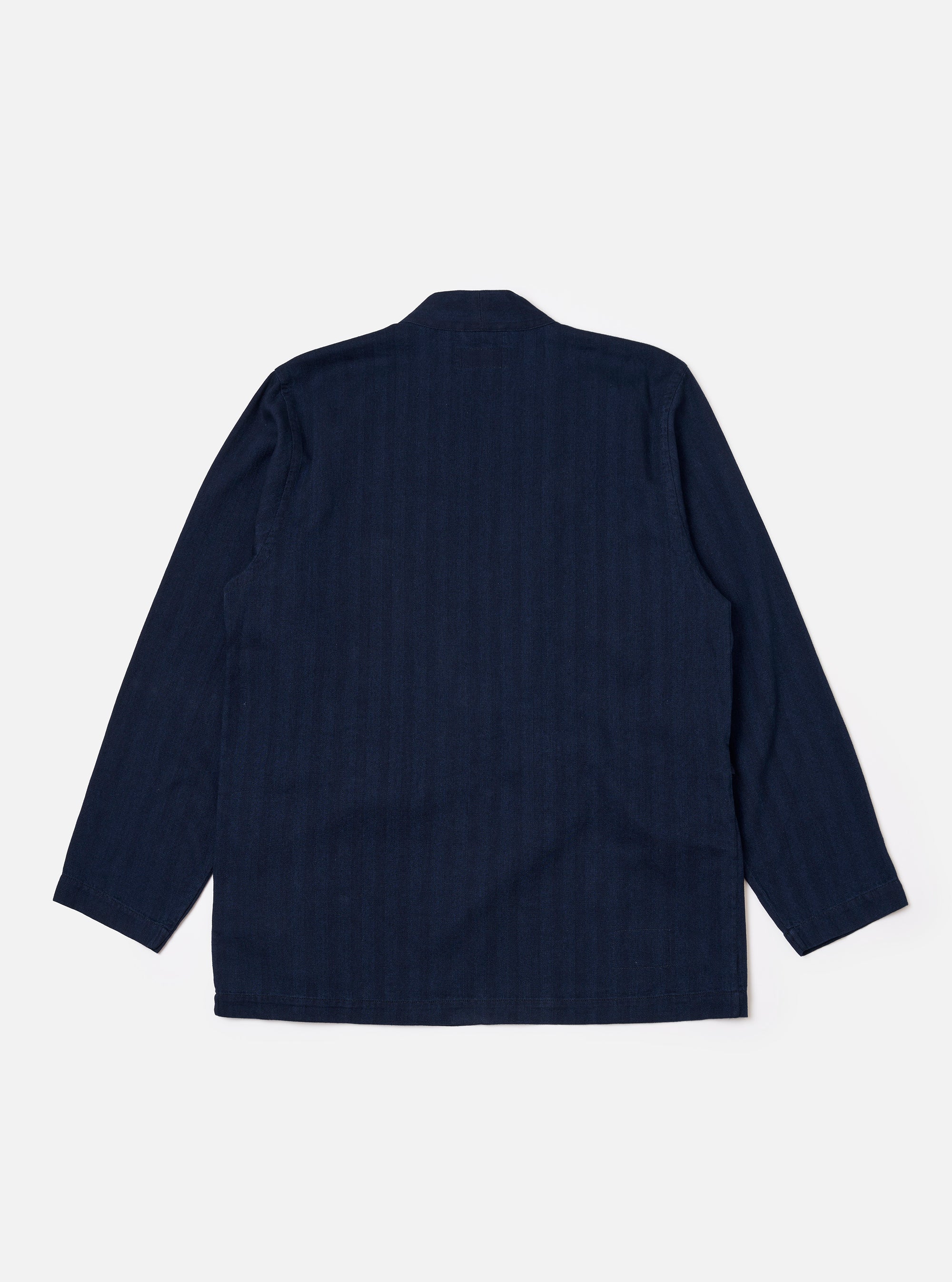The Indigo Recycled Herringbone Kyoto Work Jacket is shown from the back as a flat lay against a plain white background. The image highlights the jacket's simple rear construction, straight hem, and the textured indigo herringbone fabric.