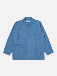 The Washed Indigo Recycled Herringbone Kyoto Work Jacket is shown as a flat lay against a white background. The jacket features a wrap-style front with fabric ties, two large patch pockets at the waist, and a single patch pocket on the left chest. The indigo-washed cotton fabric displays a distinct herringbone weave pattern.