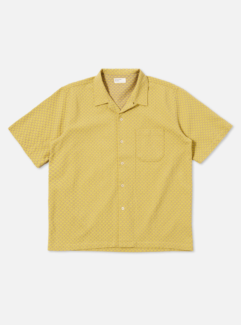 The Yellow Mykonos Cotton Road Shirt is shown as a flat lay against a white background. The shirt features a camp collar, a button-down front, and a single chest pocket. The fabric is decorated with a patterned design in shades of yellow and ochre.