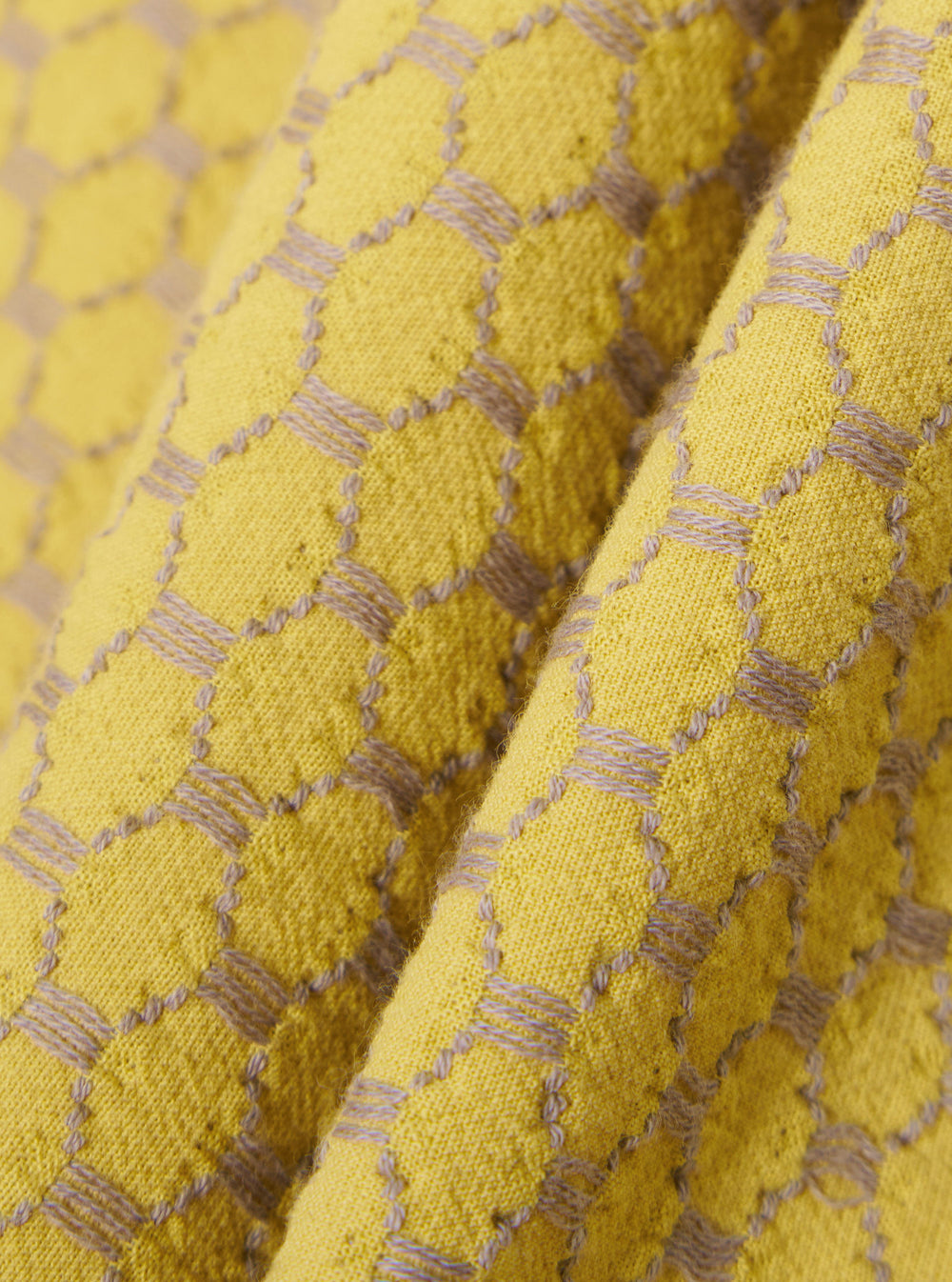 A close-up fabric swatch of the Yellow Mykonos Cotton Road Shirt highlights the detailed texture and woven pattern of the material. The fabric features a mix of yellow and ochre tones in a structured cotton weave.