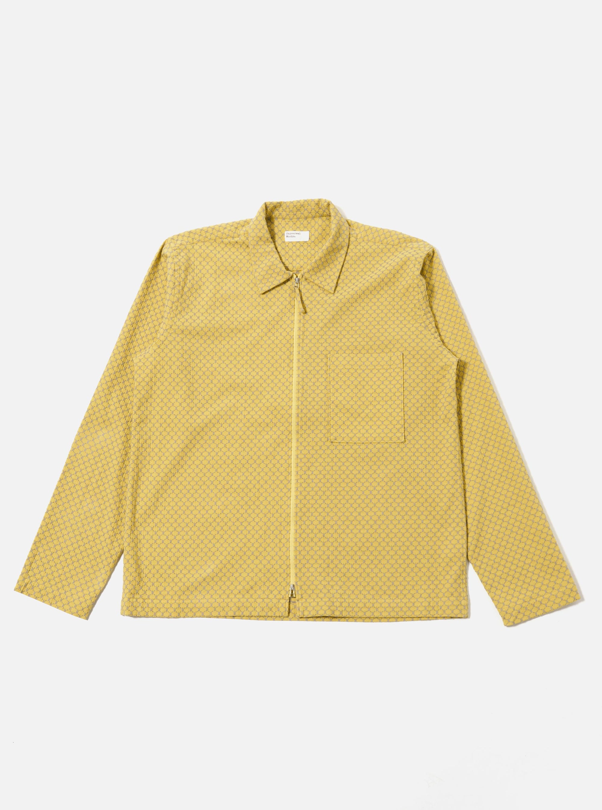 The Yellow Mykonos Cotton Zip Shirt is shown as a flat lay against a white background. The shirt features a full-length central silver zipper, a classic structured collar, and two large patch pockets at the waist. The cotton fabric is a vibrant yellow with a subtle, fine-textured weave.