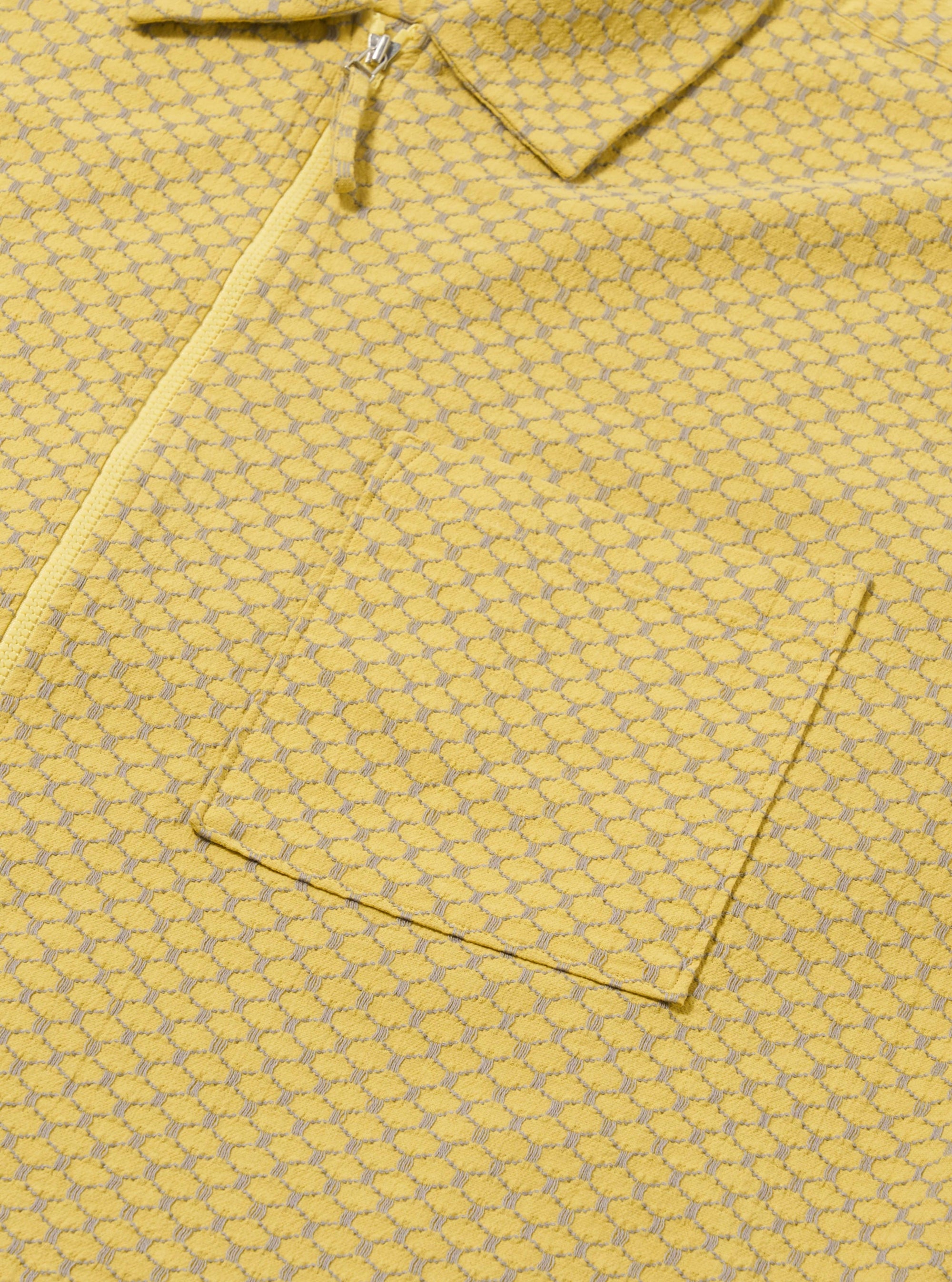 The Yellow Mykonos Cotton Zip Shirt is shown from the back as a flat lay against a plain white background. The image highlights the shirt's relaxed fit, straight hem, and the detailed pattern of the yellow Mykonos cotton fabric. A simple horizontal yoke is visible across the shoulders.