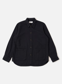 The Black Kendal Cotton Travail Overshirt is shown as a flat lay against a white background. The overshirt features a one-piece collar, a central button-down closure, and two large patch pockets at the waist. The black cotton fabric has a smooth texture, and the garment is finished with a curved hem.