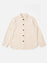 The Ecru Kendal Cotton Travail Overshirt is shown as a flat lay against a white background. The overshirt features a one-piece collar, a central button-down closure, and two large patch pockets at the waist. The garment is made from a textured ecru cotton fabric and has a curved hem with a visible contrast stitch insert.