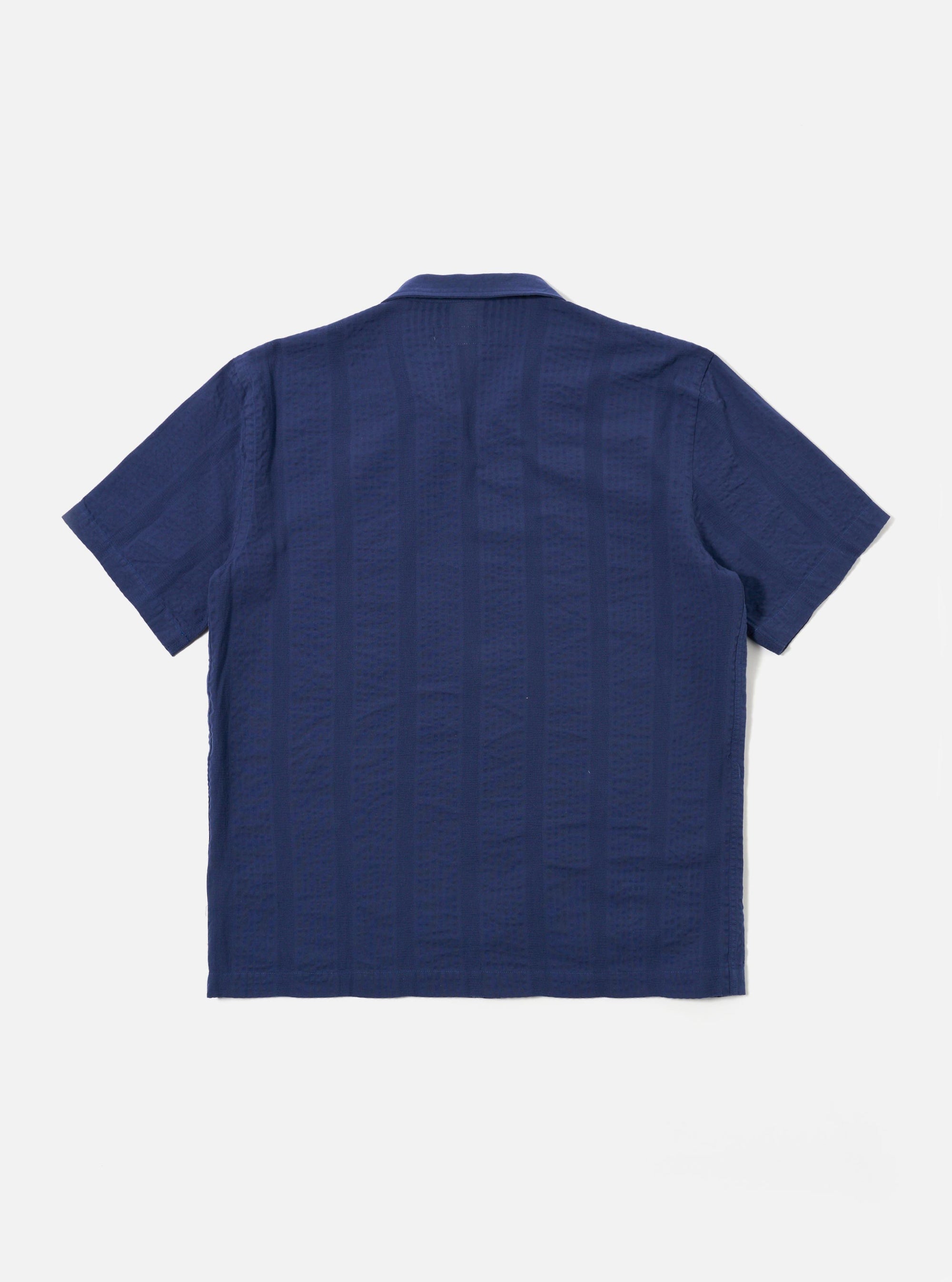The Blue Maui Cotton Road Shirt is shown from the back as a flat lay against a white background. The shirt features a straight hem with small side splits and a single-piece collar. The fabric has a distinct vertical stripe pattern in shades of blue and navy.