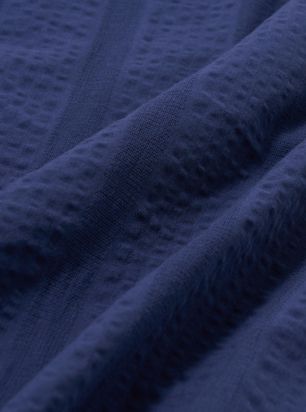A close-up fabric swatch of the Blue Maui Cotton Road Shirt. The image shows a detailed view of the light blue and white vertical striped cotton fabric, highlighting its fine weave and textured appearance.