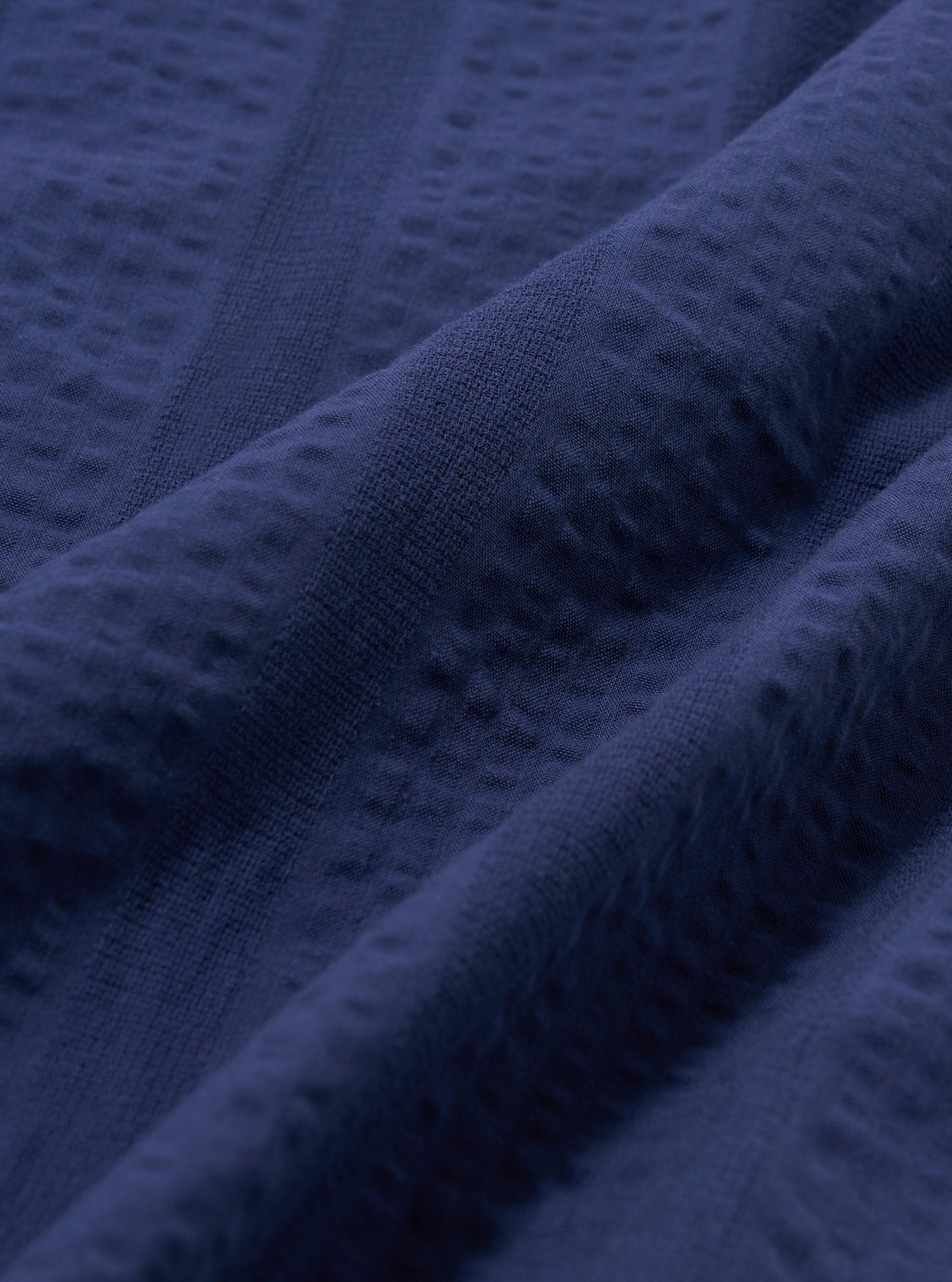 A close-up fabric swatch of the Blue Maui Cotton Road Shirt. The image shows a detailed view of the light blue and white vertical striped cotton fabric, highlighting its fine weave and textured appearance.