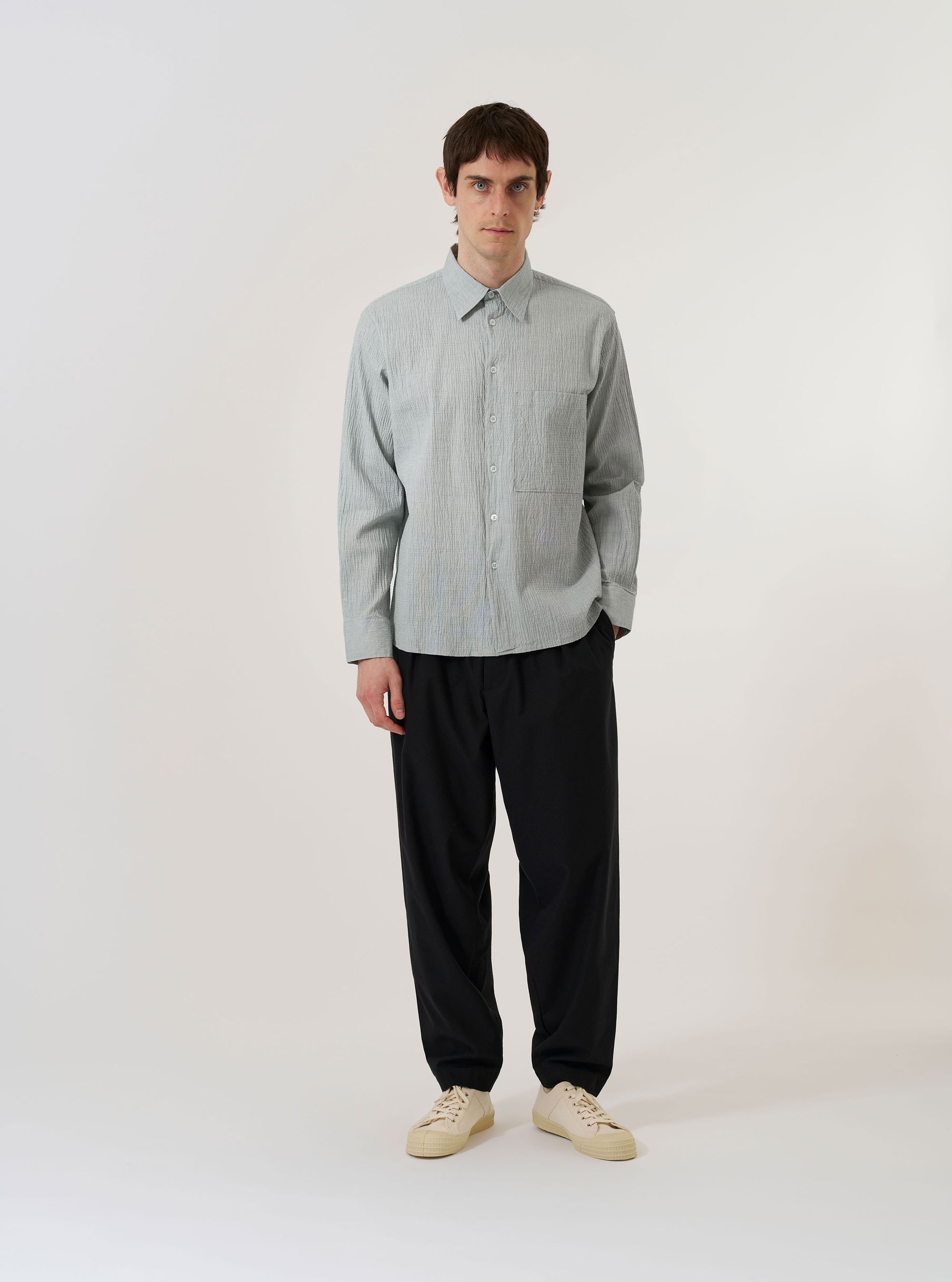 The Green Seersucker Square Pocket Shirt is displayed as a flat lay against a plain white background. The shirt features a button-down front, a structured pointed collar, and a prominent square patch pocket on the left chest. The solid green fabric has a distinct puckered seersucker texture throughout.