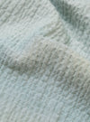 A close-up swatch image of the Green Seersucker Square Pocket Shirt fabric highlights the light green color and the distinct puckered texture of the seersucker material. The fabric fills the frame, providing a detailed view of the garment's weave and color.