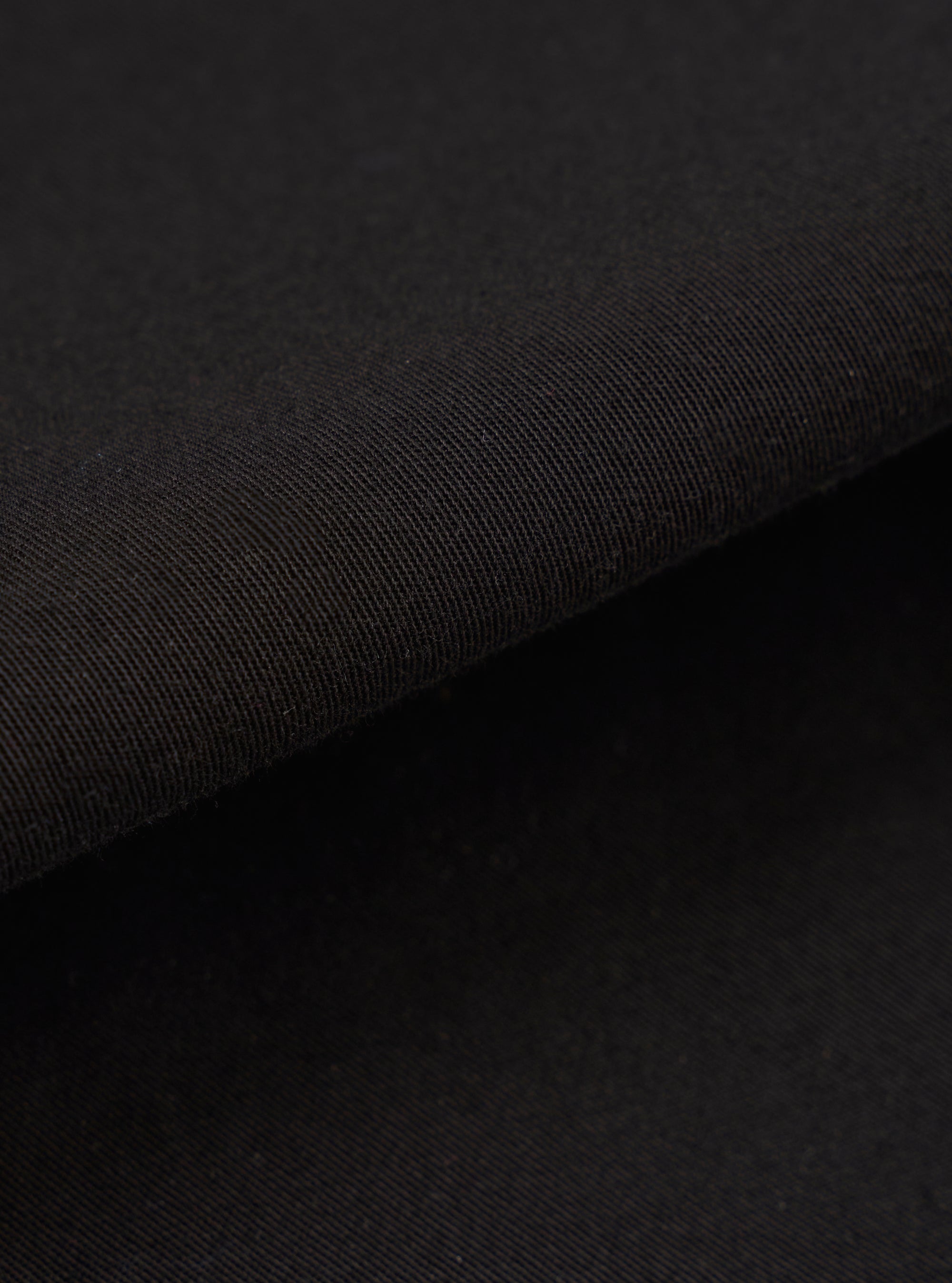 A close-up fabric swatch of the Black Kelly Cotton Judo Pant is shown, highlighting the solid black color and the natural texture of the durable cotton fabric.