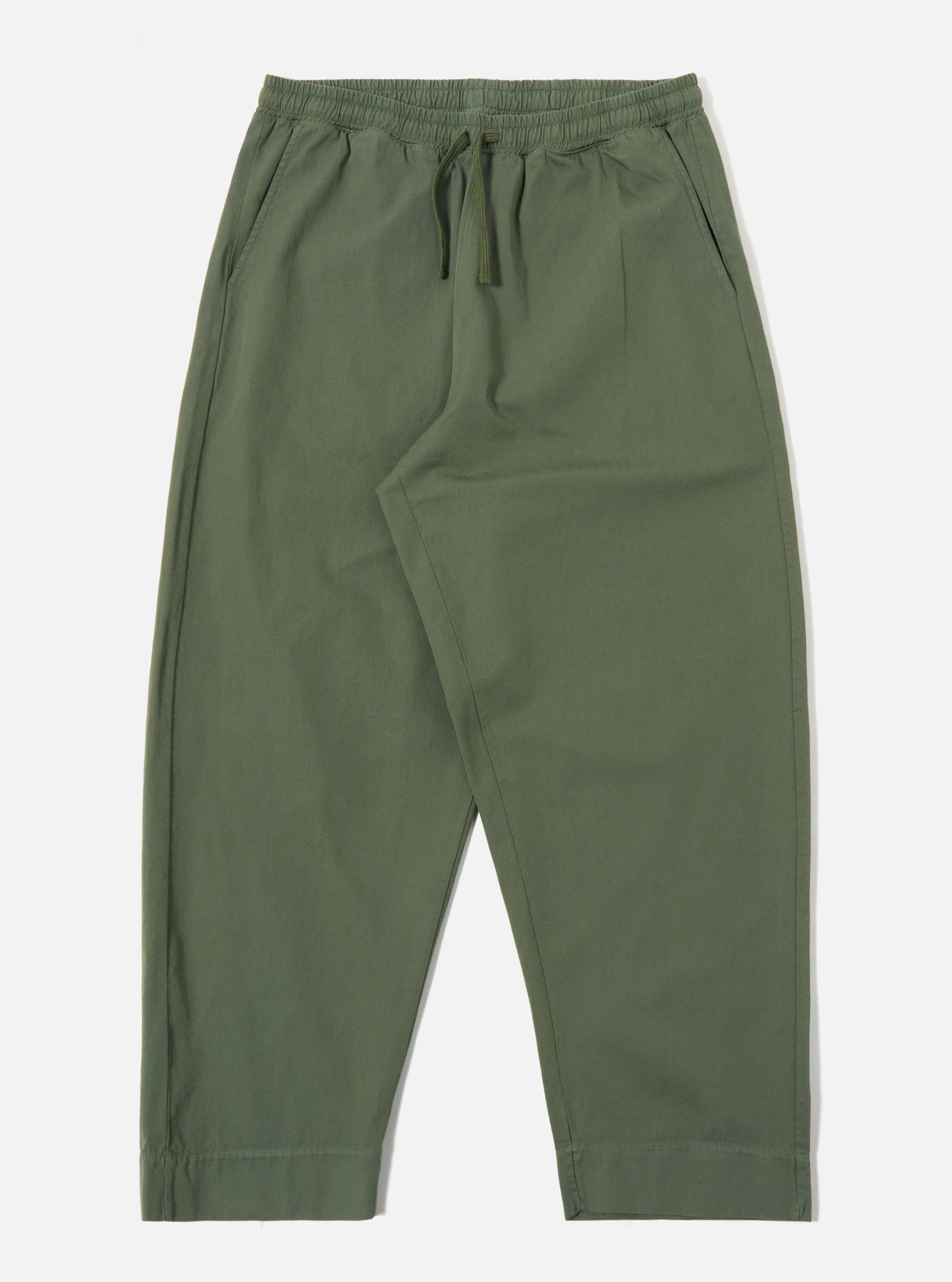 The Olive Kelly Cotton Judo Pant is shown as a flat lay against a plain white background. The trousers feature a wide, straight-leg silhouette, an elasticated waistband with an external drawstring, and two large patch pockets on the front. The fabric is a solid olive green cotton with a visible textured weave.