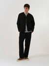 The Black Kelly Cotton Glider Jacket is shown as a flat lay against a white background. The jacket features a full-length front zipper, two large chest patch pockets with buttoned flaps, and a pointed collar. The garment is made from a solid black cotton fabric.
