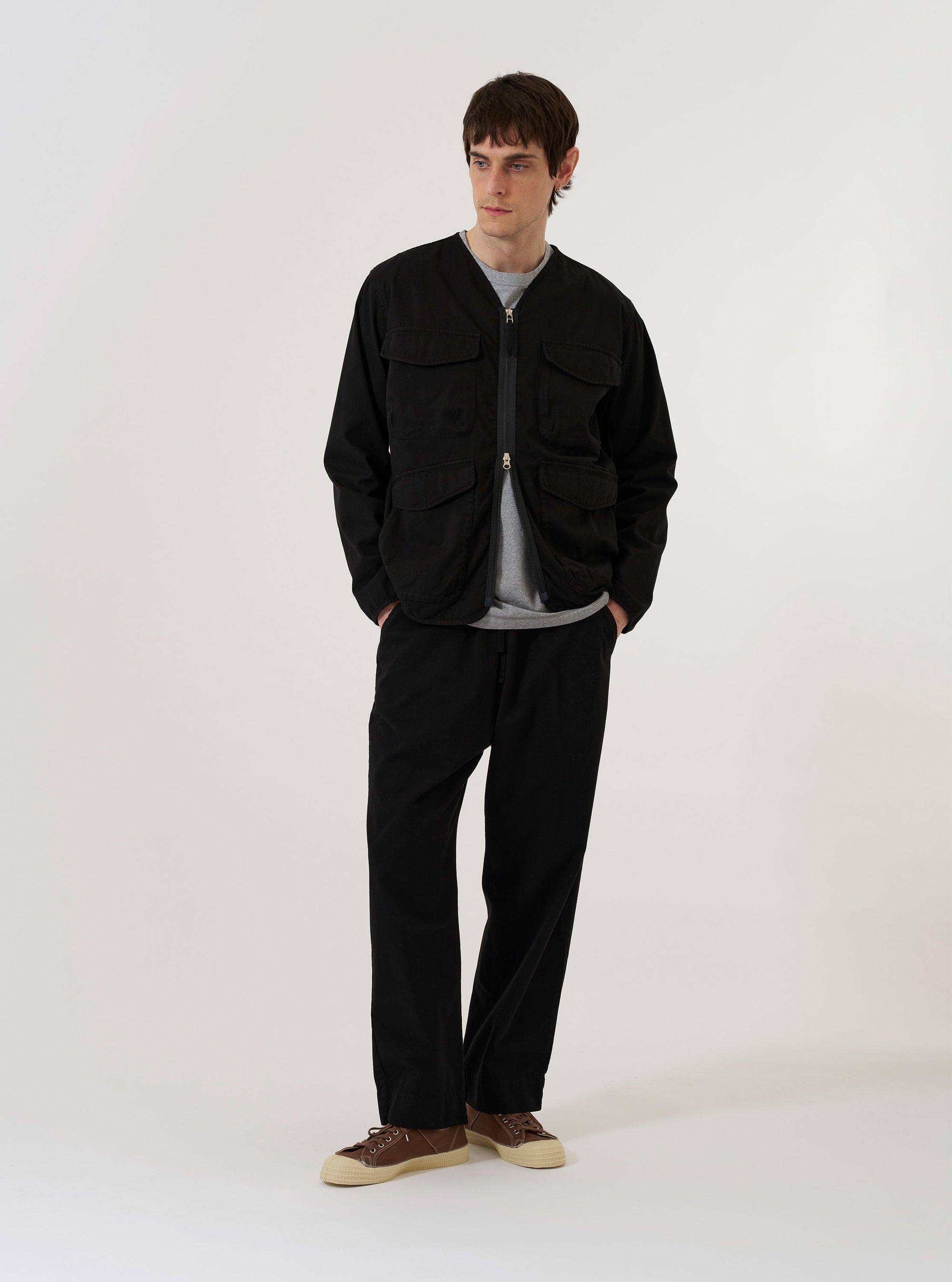 The Black Kelly Cotton Glider Jacket is shown as a flat lay against a white background. The jacket features a full-length front zipper, two large chest patch pockets with buttoned flaps, and a pointed collar. The garment is made from a solid black cotton fabric.