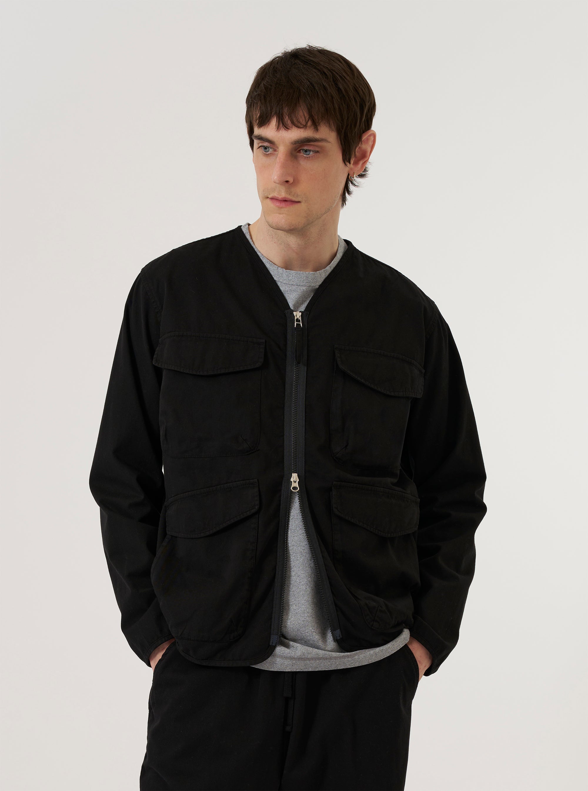 A model wears the Black Kelly Cotton Glider Jacket against a white background. The jacket features four prominent 3D bellows pockets on the front, a central exposed zipper, and bound edges. The model is shown from the front, highlighting the utility-style design of the garment.