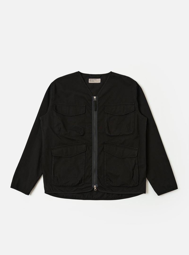 The Black Kelly Cotton Glider Jacket is shown as a flat lay against a white background. The jacket features two large chest pockets with buttoned flaps, a central button-down front, and a classic pointed collar. The fabric is a solid black cotton with visible stitching details.