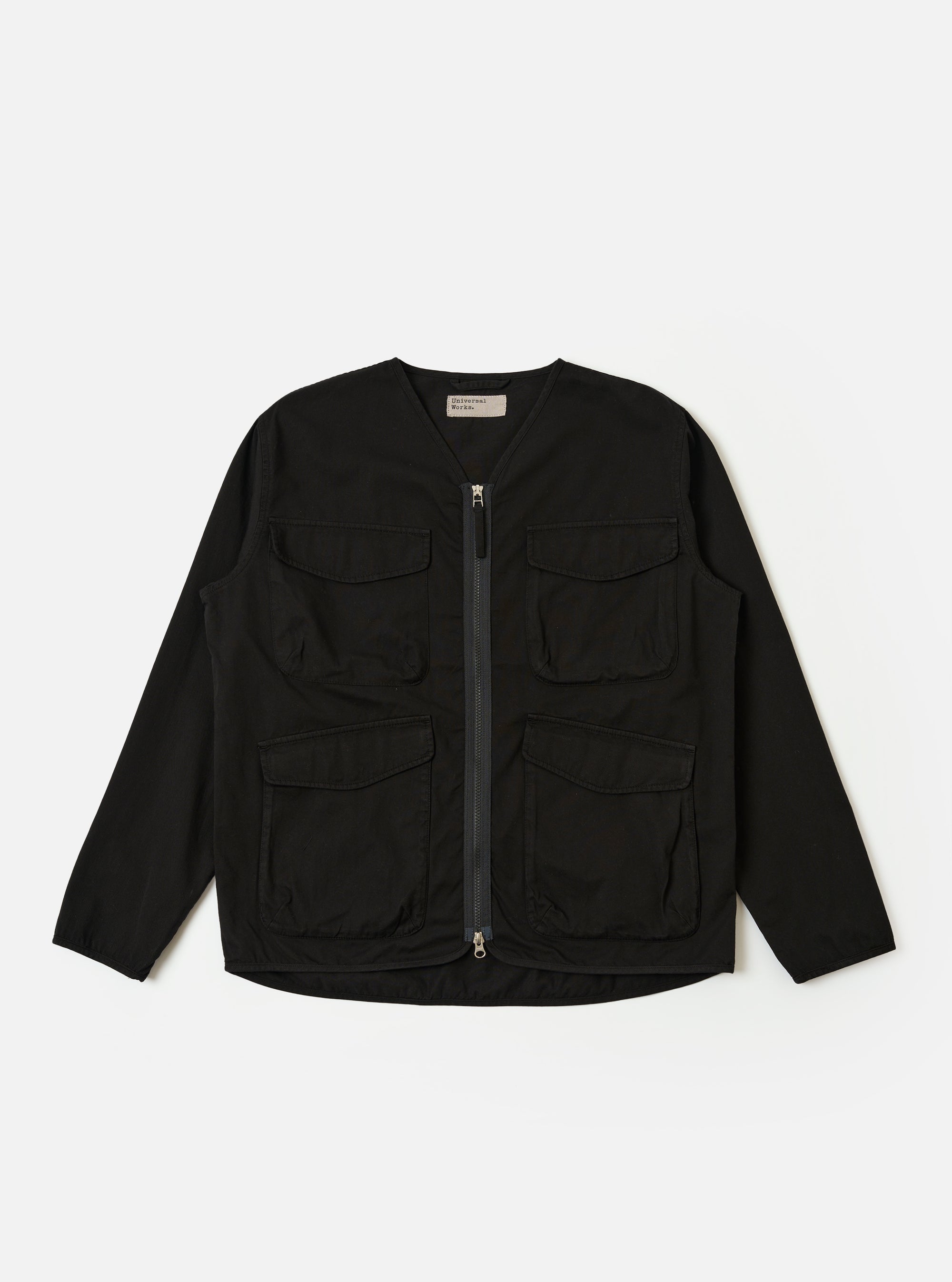 The Black Kelly Cotton Glider Jacket is shown as a flat lay against a white background. The jacket features two large chest pockets with buttoned flaps, a central button-down front, and a classic pointed collar. The fabric is a solid black cotton with visible stitching details.