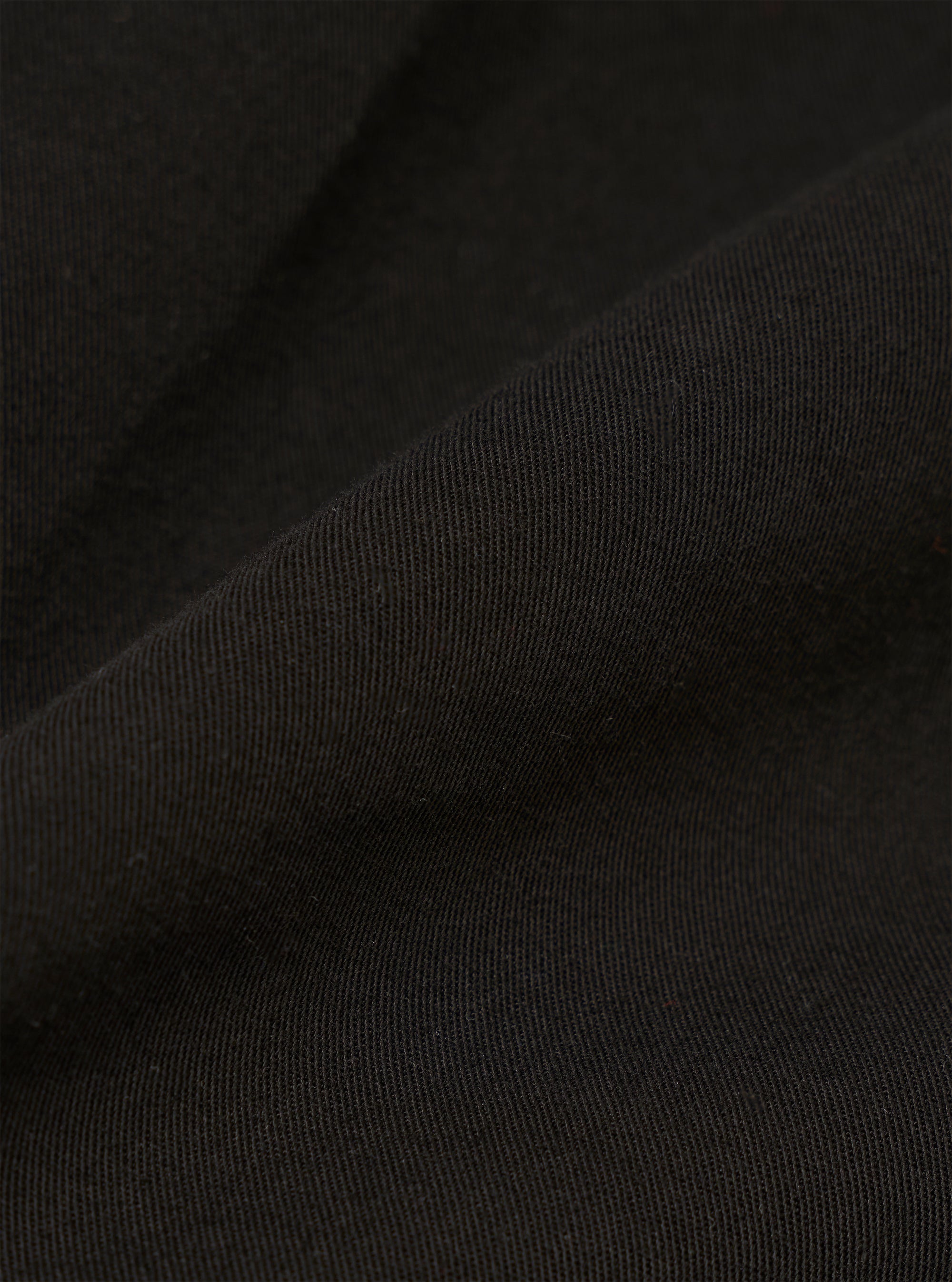 A close-up fabric swatch of the Black Kelly Cotton Glider Jacket shows the detailed texture and weave of the black cotton fabric.