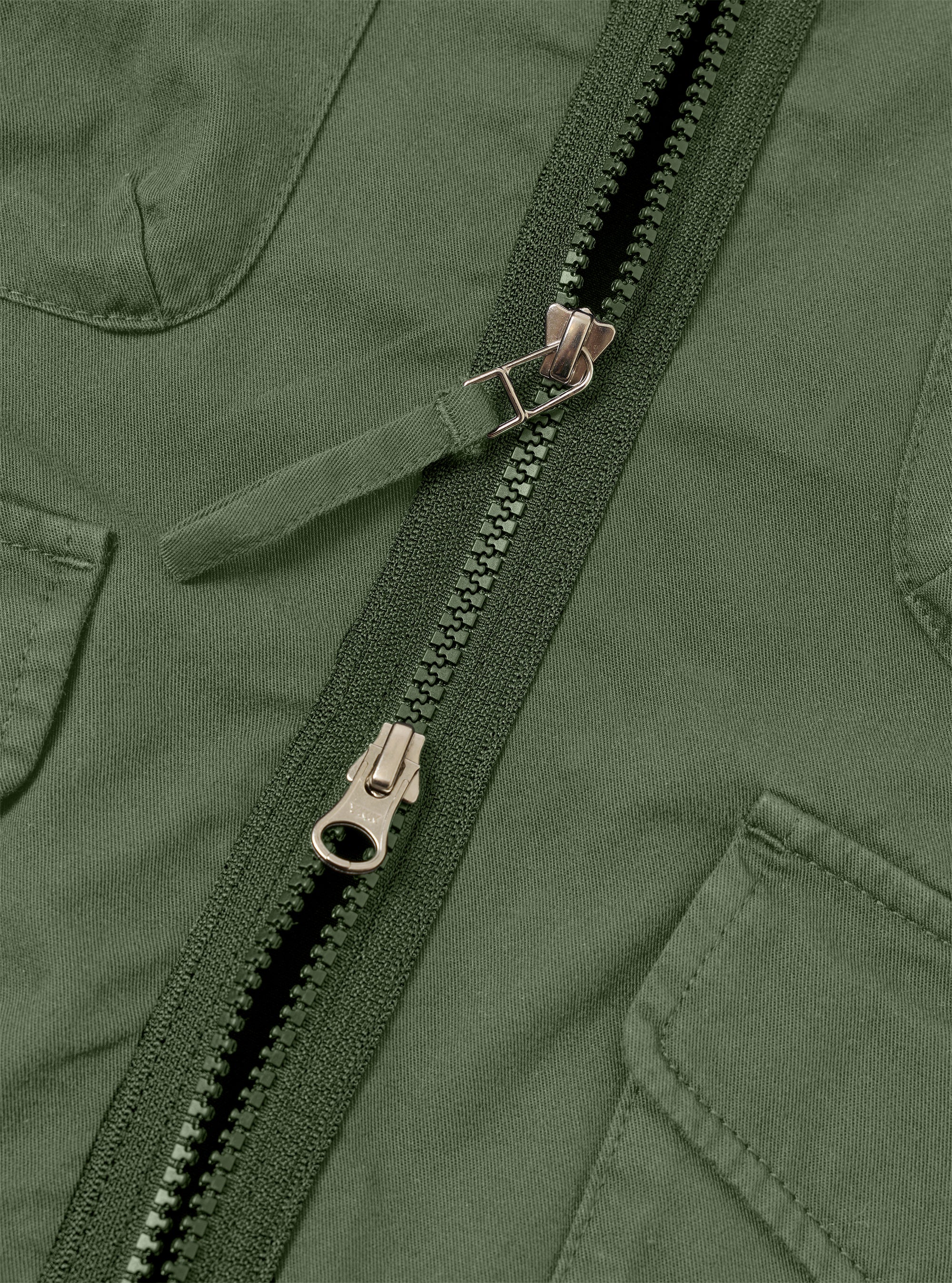 The Olive Kelly Cotton Glider Jacket is shown from the back as a flat lay against a plain white background. The image highlights the clean construction of the garment's rear panel, featuring a straight hem and simple stitching details. The olive green cotton fabric has a smooth, matte finish.