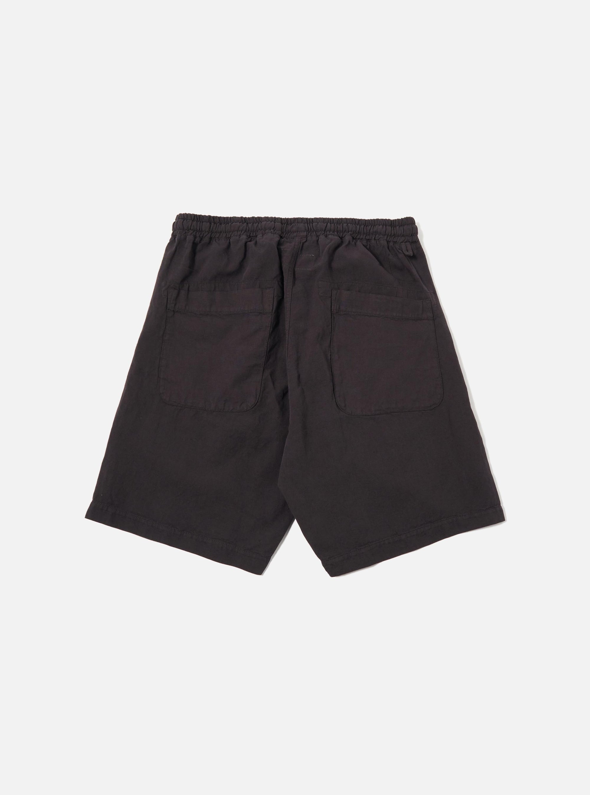 The Licorice Lyo Linen Mix Simple Short is shown as a flat lay against a white background. These brown shorts feature an elasticated waistband with an adjustable drawstring, side angled pockets, and a relaxed, wide-leg fit. The fabric has a visible textured weave characteristic of a linen-lyocell blend.