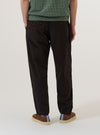 A model is wearing the Licorice Lyo Linen Mix Oxford Pant, shown from the waist down against a plain white background. The trousers feature a loose, wide-leg fit, an adjustable drawstring waistband, and pleated detailing at the front. The fabric is a dark brown licorice-colored linen and lyocell blend with a smooth, lightweight appearance.