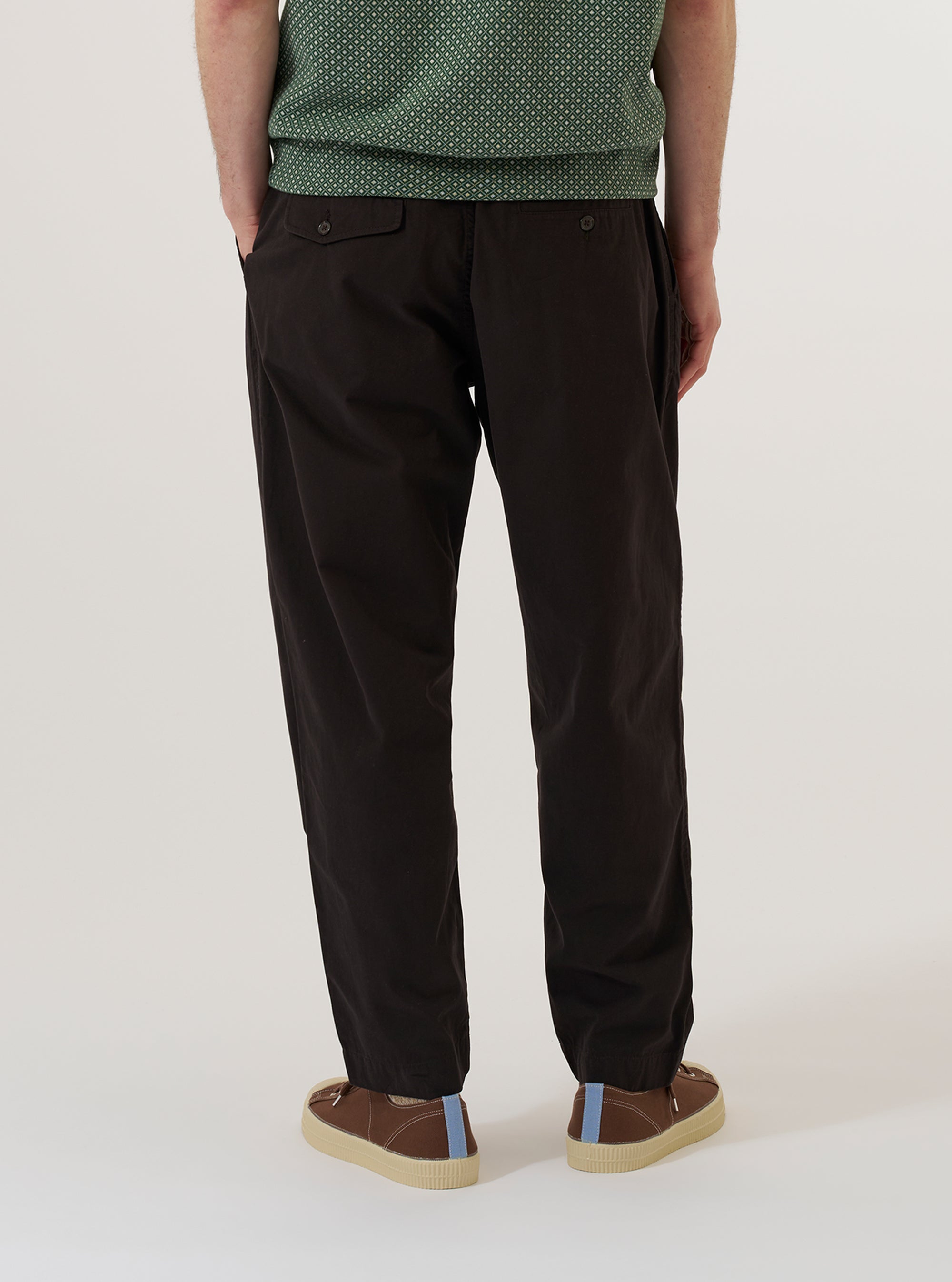 A model is wearing the Licorice Lyo Linen Mix Oxford Pant, shown from the waist down against a plain white background. The trousers feature a loose, wide-leg fit, an adjustable drawstring waistband, and pleated detailing at the front. The fabric is a dark brown licorice-colored linen and lyocell blend with a smooth, lightweight appearance.
