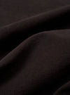 A close-up fabric swatch of the Licorice Lyo Linen Mix Coverall Jacket displays the dark brown color and the distinct texture of the linen, lyocell, and organic cotton blend. The material fills the frame, providing a detailed view of the fabric's weave.
