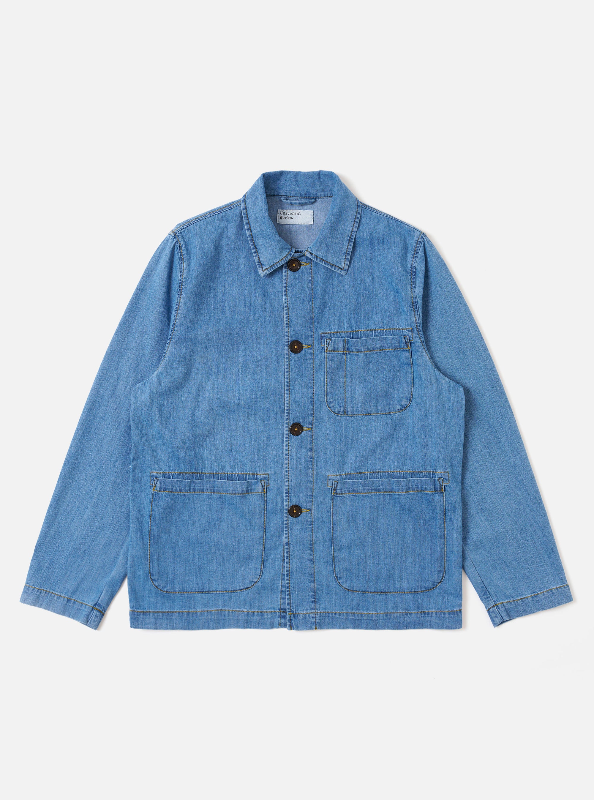 The Washed Indigo 8oz Slub Denim Field Jacket is shown as a flat lay against a white background. The jacket features a relaxed fit with a classic collar, a central button-down closure, and three front patch pockets, including one at the chest and two at the waist. The 8oz slub denim fabric has a visible textured finish and a washed indigo color with subtle fading along the seams.