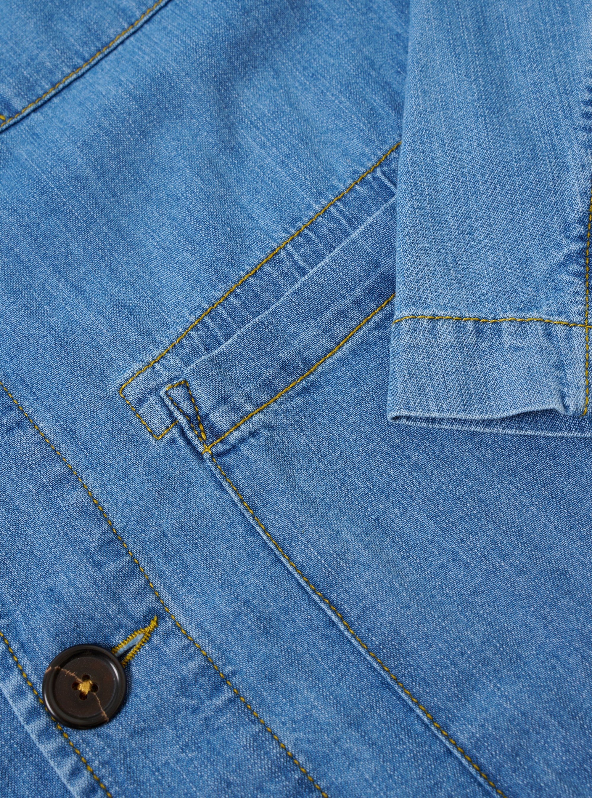 The Washed Indigo 8oz Slub Denim Field Jacket is shown from a rear angle as a flat lay against a plain white background. The image highlights the clean construction of the back panel, the straight hem, and the textured appearance of the washed indigo slub denim fabric.