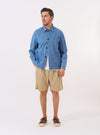 The Washed Indigo 8oz Slub Denim Field Jacket is shown as a flat lay against a white background. The jacket features a classic collar, a central four-button closure, and four large front patch pockets. The 8oz slub denim fabric has a textured, medium-blue washed appearance with visible stitching details.
