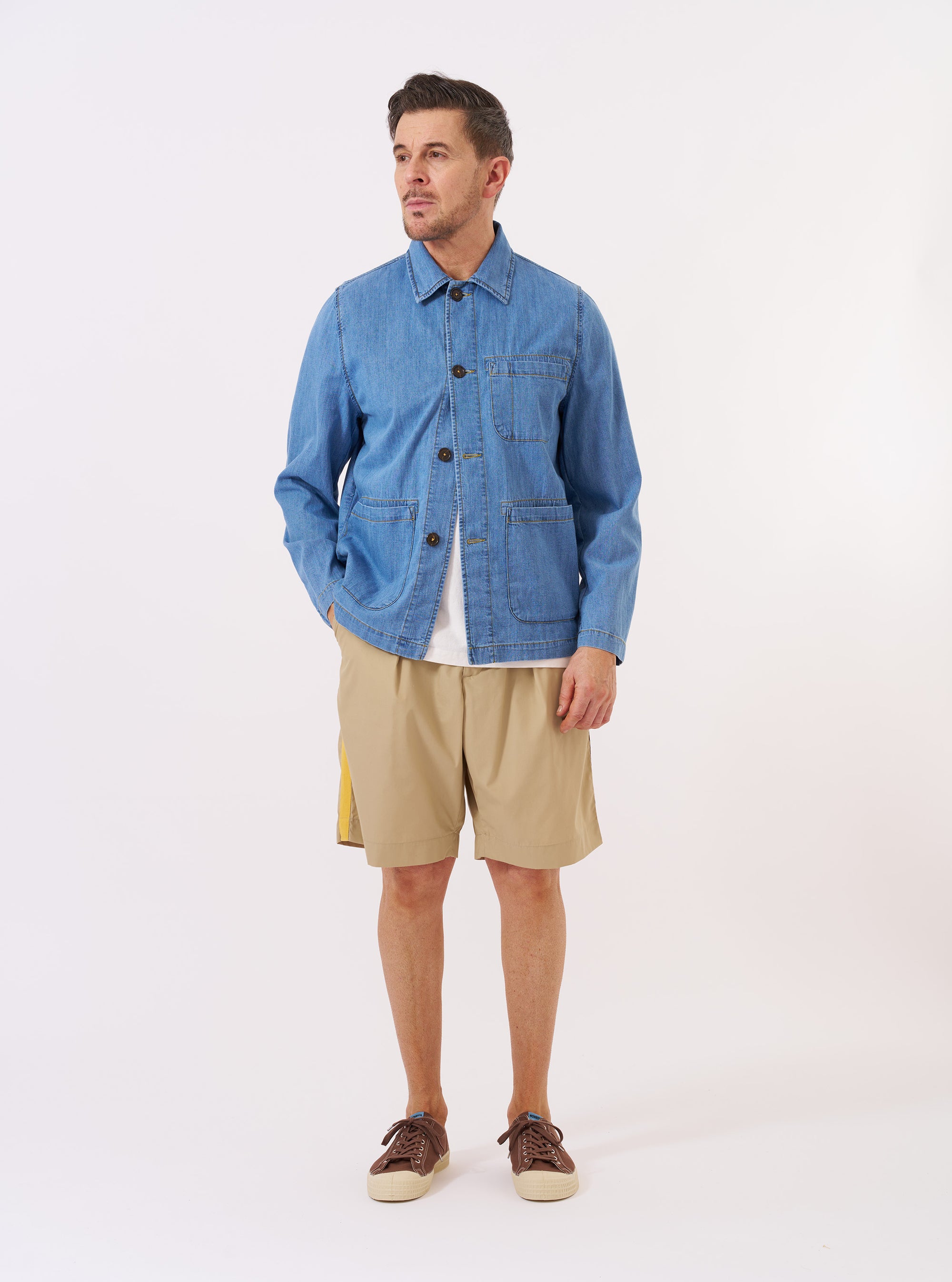 The Washed Indigo 8oz Slub Denim Field Jacket is shown as a flat lay against a white background. The jacket features a classic collar, a central four-button closure, and four large front patch pockets. The 8oz slub denim fabric has a textured, medium-blue washed appearance with visible stitching details.