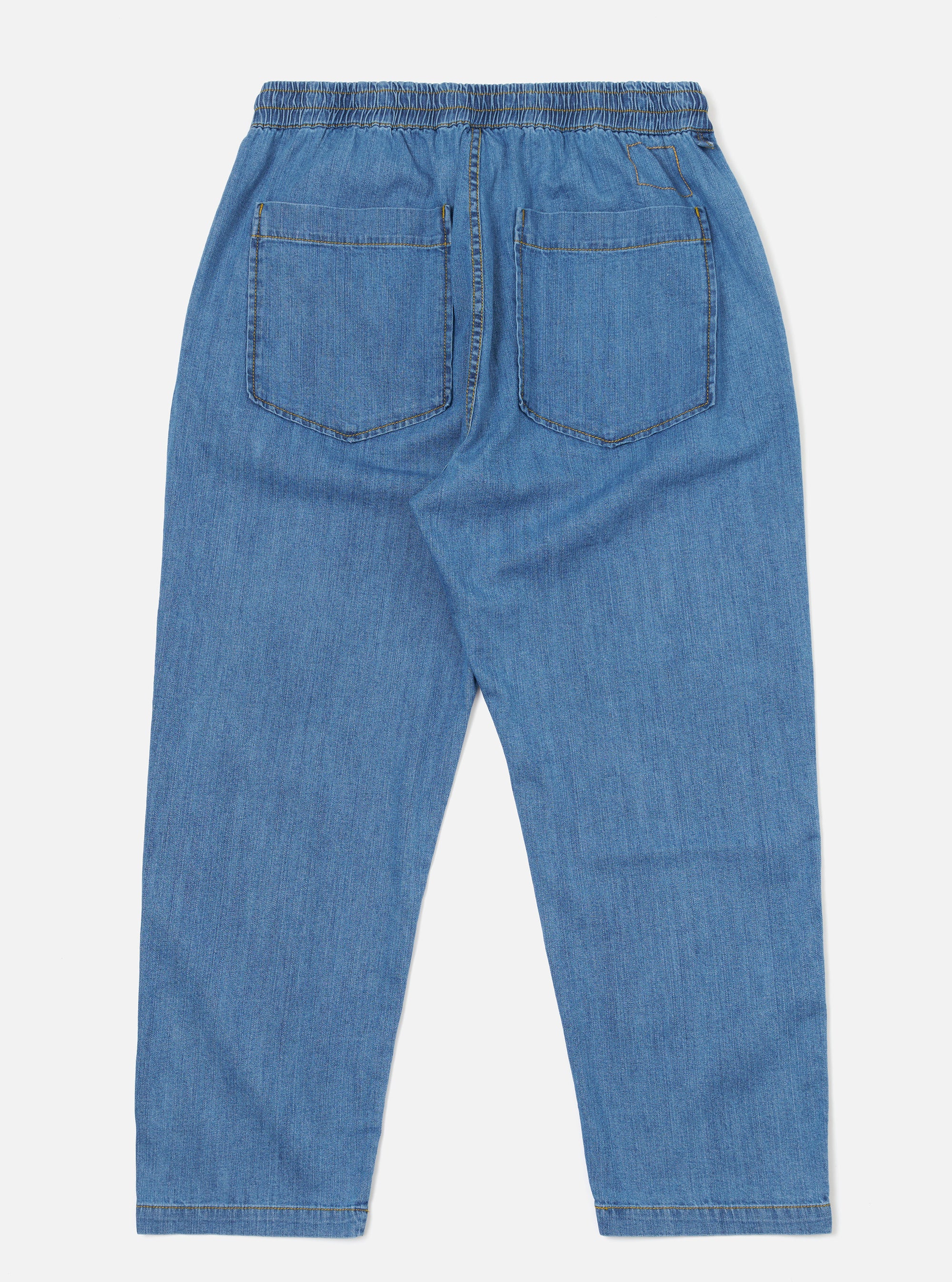 The Washed Indigo 8oz Slub Denim Hi Water Trouser is shown from the back as a flat lay against a plain white background. The image highlights the two rear patch pockets and the drawcord adjustable waistband. The 8oz slub denim fabric has a heavily washed, vintage appearance with a visible textured finish and a slightly cropped leg length.