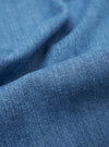 A close-up swatch image of the Washed Indigo 8oz Slub Denim Hi Water Trouser fabric highlights the textured, slubbed surface and the variations of the indigo blue wash. The weave of the 8oz denim is clearly visible, showing a mix of light and dark blue tones.