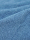 A close-up swatch of the Washed Indigo Recycled Herringbone Pleated Track Short highlights the texture and herringbone weave of the washed indigo-colored fabric. The material fills the frame, providing a detailed view of the garment's color and construction.