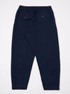 The Indigo Recycled Herringbone Pleated Track Pant is shown from the back as a flat lay against a plain white background. The image highlights the elasticated waistband and the two rear patch pockets. The indigo-colored fabric features a visible herringbone weave and tonal stitching.