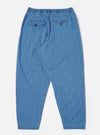 The Washed Indigo Recycled Herringbone Pleated Track Pant is shown from the back as a flat lay against a plain white background. The image highlights the elasticated waistband and the two rear pockets, one of which features a buttoned flap. The washed indigo fabric has a visible herringbone texture.