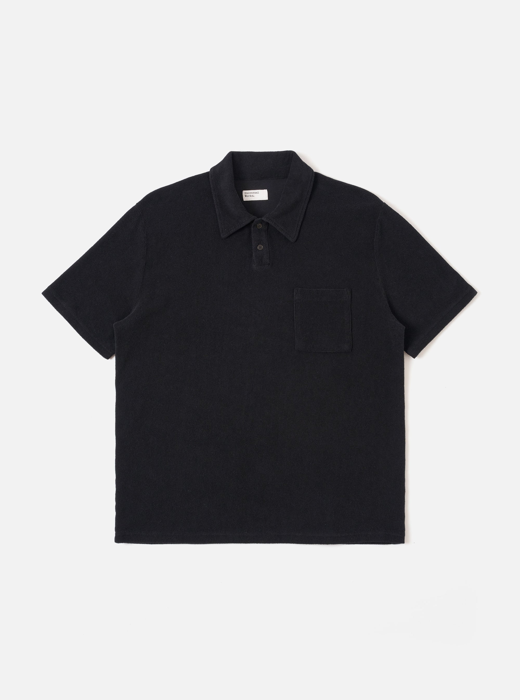 The Black Light Weight Terry Newlyn Polo is shown as a flat lay against a white background. The polo features a self-fabric collar, a two-button placket, and a single square chest pocket. The black fabric has a soft, textured terry cloth appearance with visible fine loops.