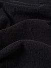 A close-up fabric swatch of the Black Light Weight Terry Newlyn Polo highlights the plush, looped texture of the fine terry cloth. The image focuses on the deep black color and the soft, technical detail of the material.