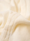 The Ecru Light Weight Terry Newlyn Polo is shown in a close-up detail shot against a plain white background. The image focuses on the soft, looped texture of the ecru terry cloth fabric, highlighting the clean stitching of the hem and the side of the garment.