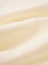A close-up fabric swatch of the Ecru Light Weight Terry Newlyn Polo highlights the off-white color and the soft, looped texture of the lightweight terry cloth. The material fills the frame, providing a detailed view of the garment's pile and construction.