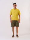 The Yellow Light Weight Terry Newlyn Polo is presented as a flat lay against a plain white background. The polo features a classic collar, a three-button placket, and short sleeves, crafted from a textured yellow light weight terry fabric.