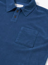 The Navy Light Weight Terry Newlyn Polo is displayed from the back as a flat lay against a plain white background. The image highlights the simple one-piece collar, the straight hem with side splits, and the soft texture of the navy blue light weight terry fabric.