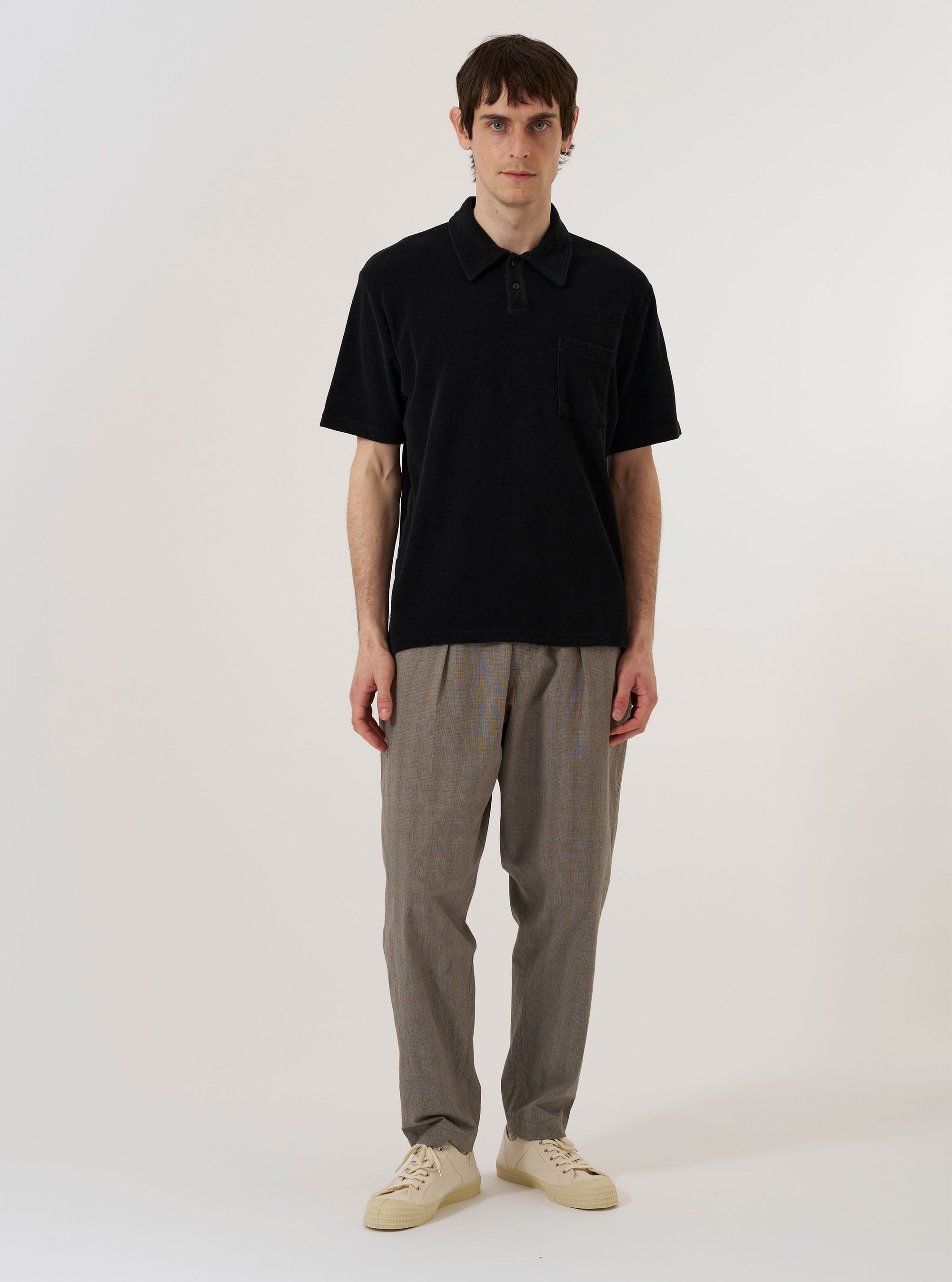 The Black Light Weight Terry Newlyn Polo is shown as a flat lay against a plain white background. The polo features a classic collar and a V-neck style placket, highlighting the soft, textured appearance of the black light weight terry fabric.