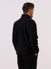 A model wears the Black Alvar Fleece Lancaster Jacket, shown from the rear against a plain white background. The jacket features a rounded shawl collar, a straight hem, and a relaxed fit. The black fabric has a distinct, curly fleece texture. No mannequin is present in the image.