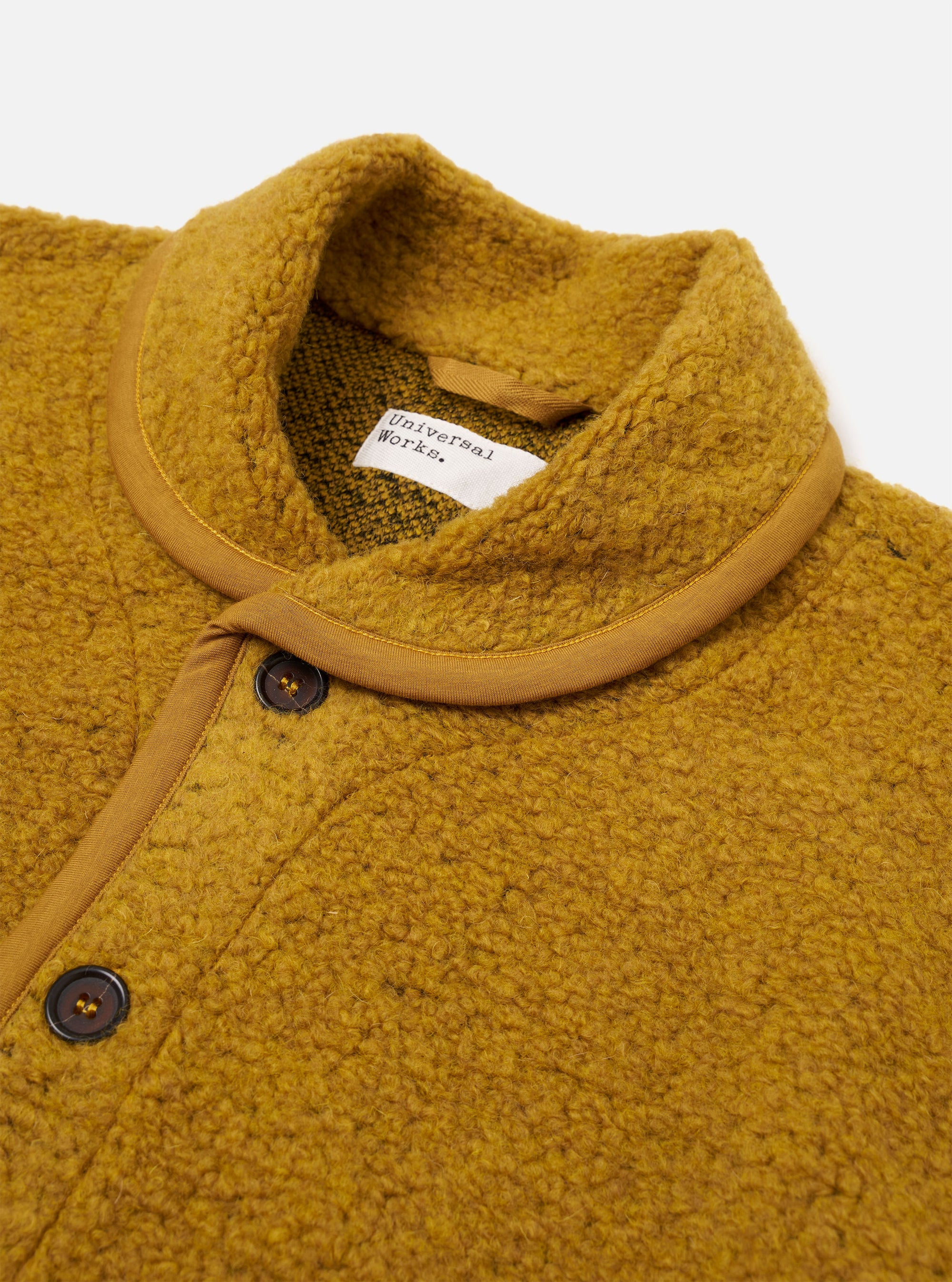 The Yellow Alvar Fleece Lancaster Jacket is shown as a flat lay against a plain white background. The jacket is crafted from a textured fleece fabric in a vibrant yellow hue and features a rounded shawl collar, a central button-down front, and large patch pockets.