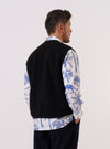 A model is wearing the Black Alvar Fleece Lancaster Gilet over a light-colored long-sleeve top, shown from the back against a plain white background. The gilet features a soft, curly fleece texture in black and a relaxed fit with a straight hem. The sleeveless design and rounded shoulders are prominent in this rear-view image. No mannequin is present.
