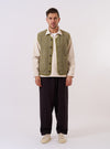 The Light Olive Alvar Fleece Lancaster Gilet is shown as a flat lay against a plain white background. The gilet features a textured, curly fleece fabric in a light olive green, a curved shawl collar, and a six-button front closure. Two large patch pockets are visible at the waist, and the edges of the garment are finished with tonal jersey binding.