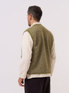 A model wears the Light Olive Alvar Fleece Lancaster Gilet over a light-colored shirt, shown from a rear three-quarter angle against a plain white background. The gilet features a sleeveless design with a straight hem and is made from a textured, light olive green fleece fabric. The model is standing with their back partially turned to the camera to highlight the garment's fit and rear construction.