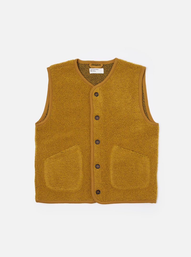 The Yellow Alvar Fleece Lancaster Gilet is presented as a flat lay against a plain white background. The gilet features a deep V-neckline, a five-button front closure, and two large patch pockets at the waist. The fabric has a distinct, richly textured looped weave in a vibrant yellow-ochre shade with simple tonal binding along the edges.